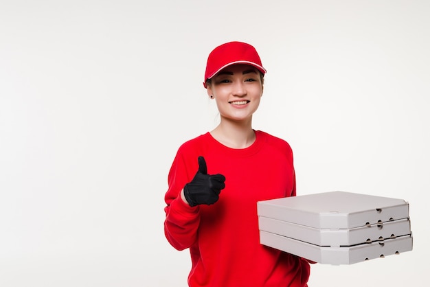 Азиатская женщина доставки пиццы с большими пальцами руки вверх, держа пиццу над изолированной на белом