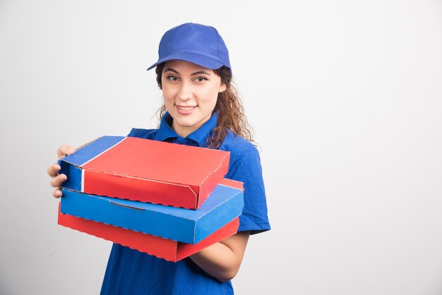 Pizza delivery girl holding three boxes on white background. High quality photo
