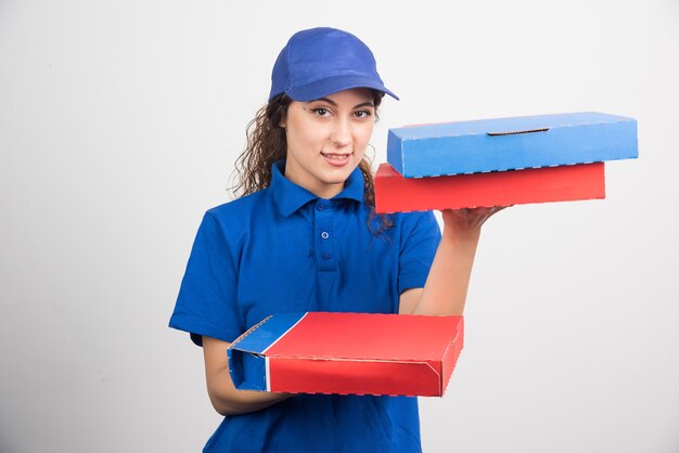 白い背景の上の3つのボックスを保持しているピザ配達の女の子。高品質の写真