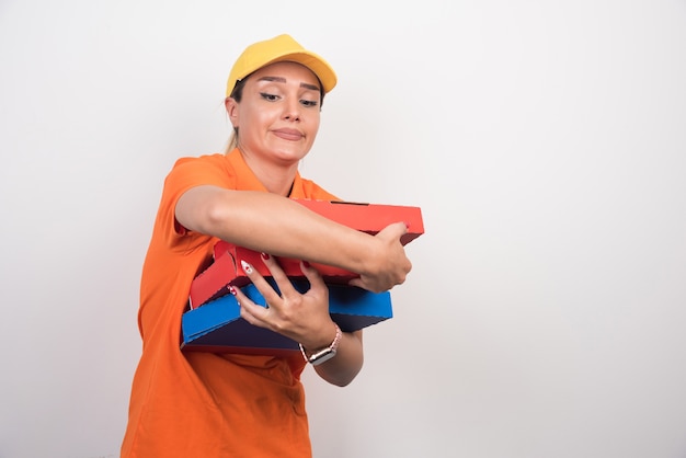 Pizza delivery woman carefully holding pizza boxes on white background.