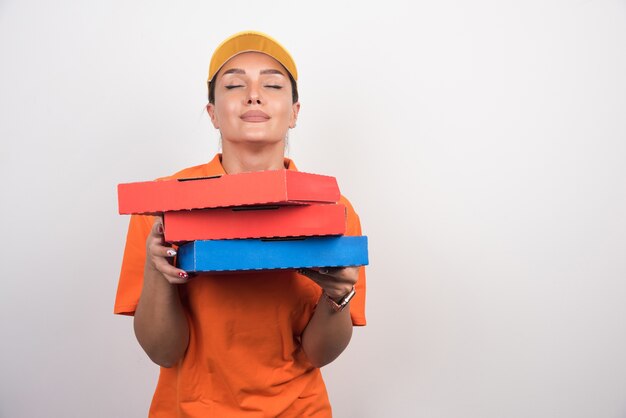 Pizza delivery woman holding pizza boxes with peaceful face.