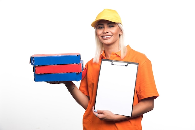 Женщина доставки пиццы держа пиццу и тетрадь на белой предпосылке. Фото высокого качества