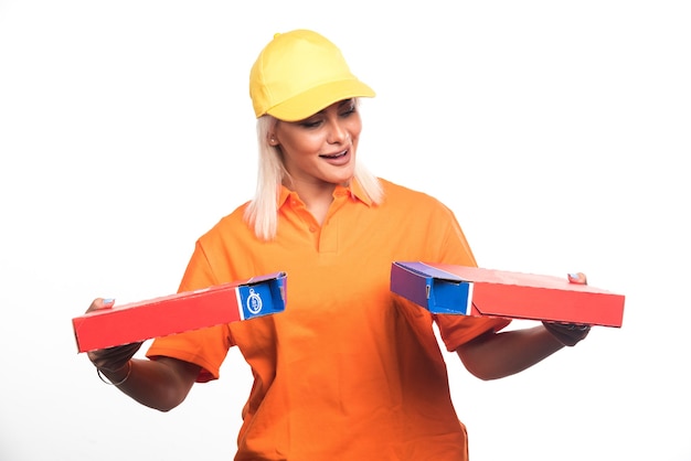 Pizza delivery woman holding pizza on white background while looking them. High quality photo