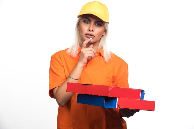 Женщина доставки пиццы, держащая пиццу на белом фоне, думая. Фото высокого качества