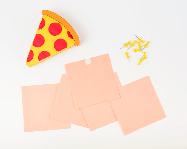 Pizza slice; adhesive notes and push pins on white backdrop