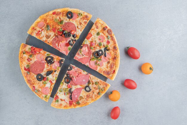 pizza slices on a platter next to small tomatoes on marble 