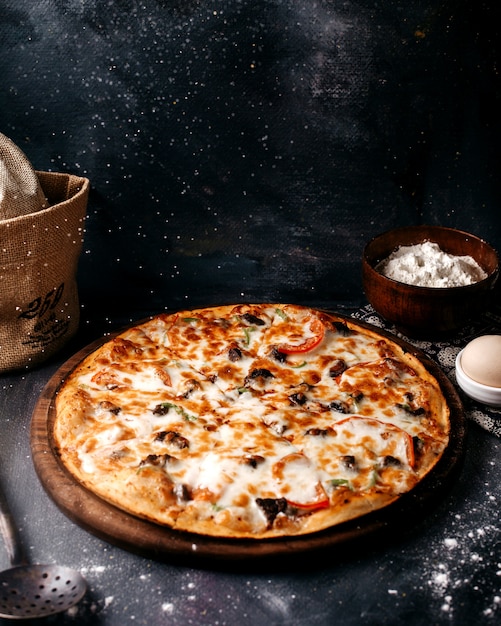 Pizza with cheese on the brown wooden surface on the bright surface