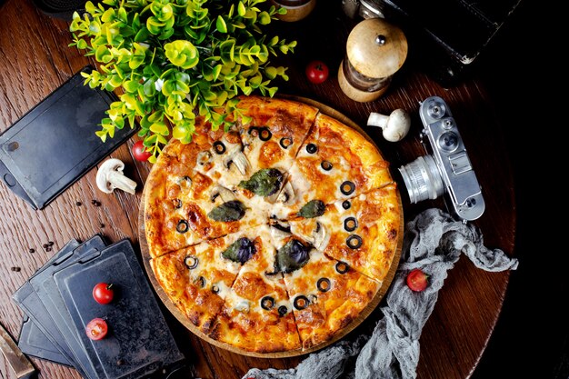 Pizza with mushrooms, olives and basil leaves