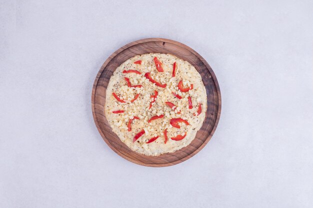 Pizza with peppers on wooden plate