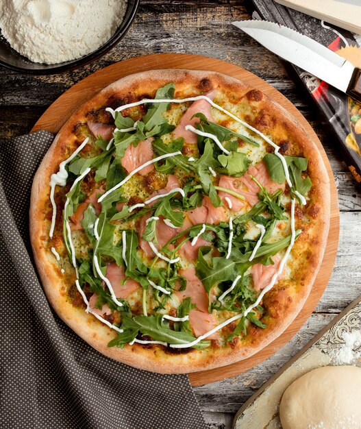 Pizza with salmon and ruccola on the table