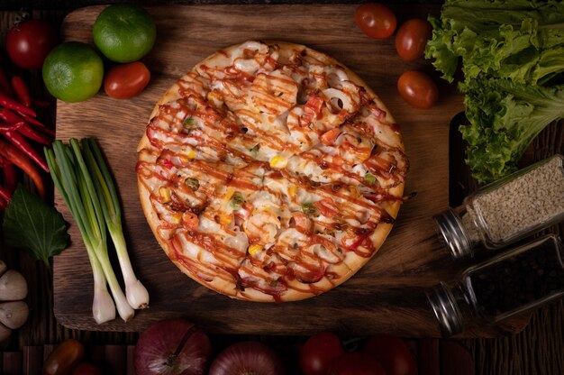 Pizza with sausage, corn, beans, shrimp and bacon on a wooden plate