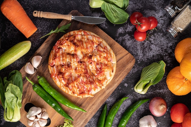 Pizza con salsiccia, mais, fagioli, gamberetti e pancetta su un piatto di legno