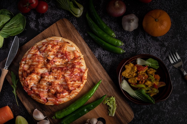 ソーセージ、トウモロコシ、豆、エビ、ベーコンを木の板に載せたピザ