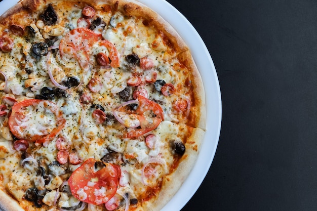 Pizza with sausages, tomato, cheese, olives and pepper