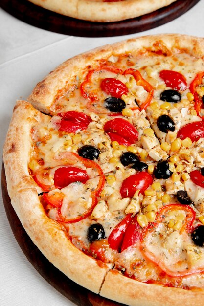 Pizza with tomatoes olives bell peppers and corn