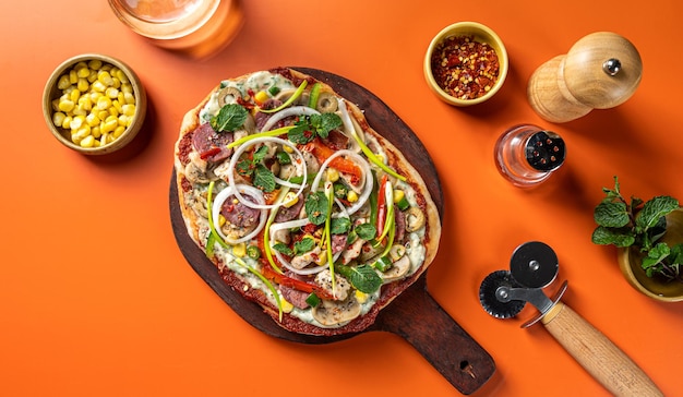 野菜、鶏肉、マッシュルーム、ハム、オリーブを木の板に平らに置いたピザ