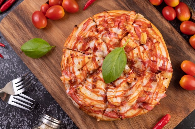 トマトチリとバジルの木製トレイのピザ。