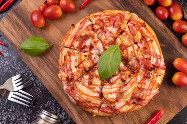 Pizza in a wooden tray with tomatoes Chili and basil.