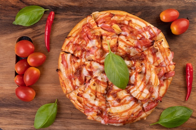 Foto gratuita pizza in un vassoio di legno con pomodori peperoncino e basilico.