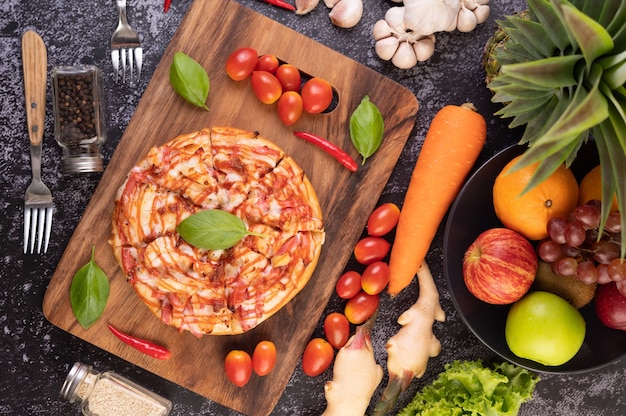 Pizza in a wooden tray with tomatoes Chili and basil.