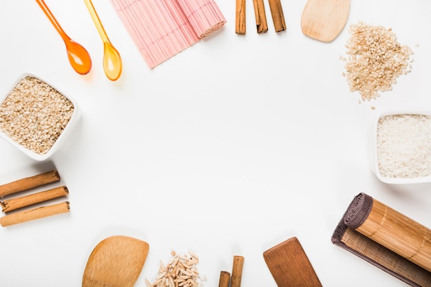 Placemat; spoon; uncooked rice; cinnamon sticks; spatula on white background