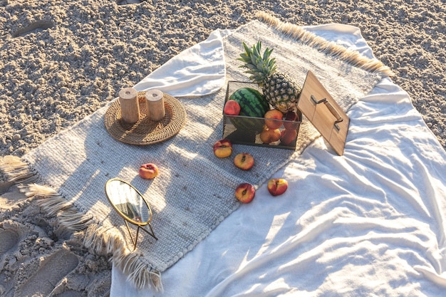 Free photo plaid with fruits on the sandy seashore picnic by the sea