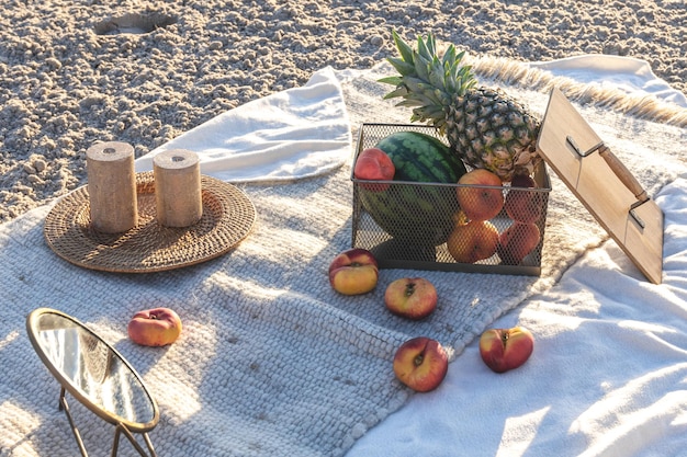 Free photo plaid with fruits on the sandy seashore picnic by the sea