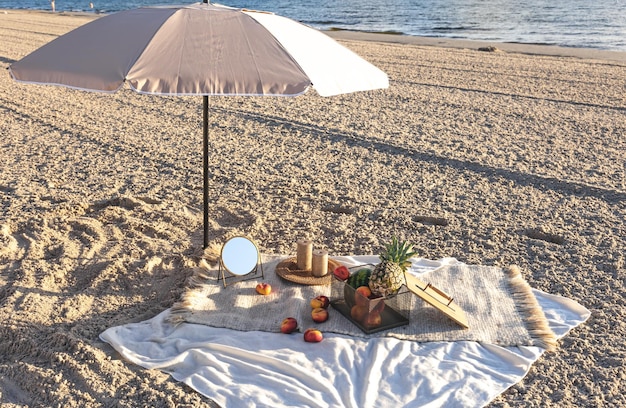 Foto gratuita plaid con frutta sul picnic in riva al mare sabbioso in riva al mare