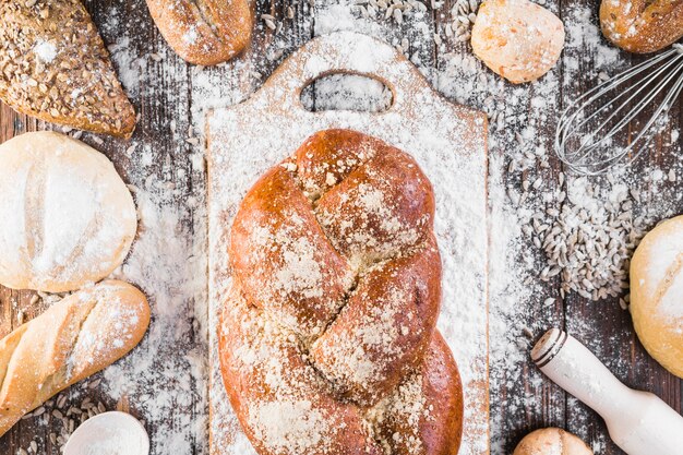 Plaited bread loaf on chopping board with flour over the table