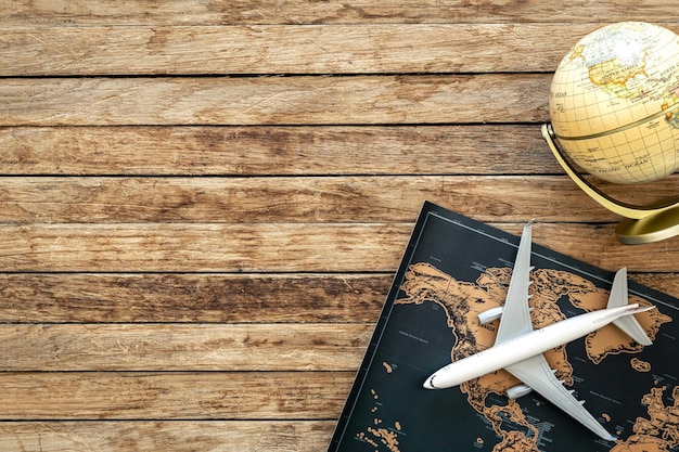 Plane map and globe on wooden background top view