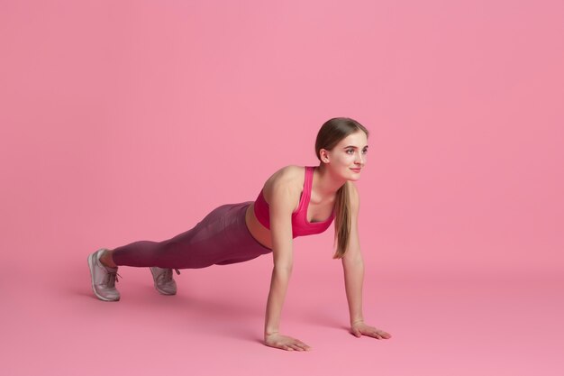 플랭크 균형. 스튜디오에서 연습하는 아름다운 젊은 여성 운동선수, 흑백 분홍색 초상화.
