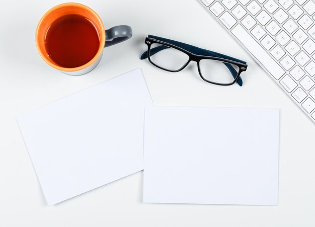 Planning concept with a cup of tea, eyeglasses, paper, keyboard on white background, space for text, top view. horizontal image