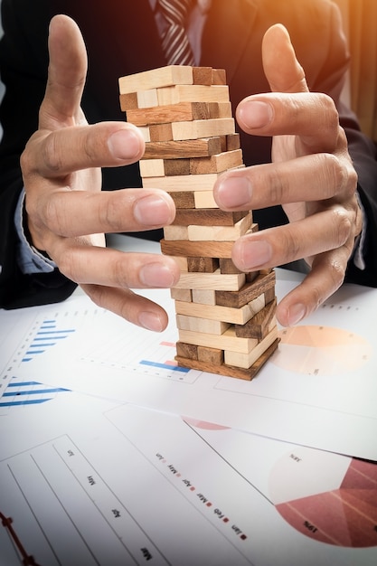 ビジネスコンセプト、タワーに木製のブロックを配置する賭博ビジネスマンで計画、リスクと戦略。