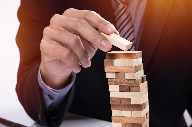 Free photo planning, risk and strategy in business concept, businessman gambling placing wooden block on a tower.