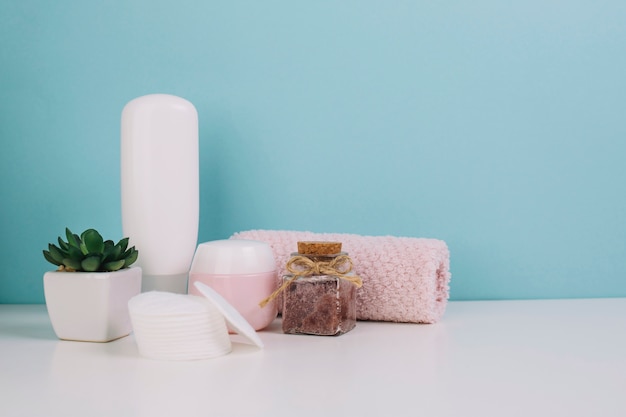 Plant and cosmetics bottles near towel and cotton pads