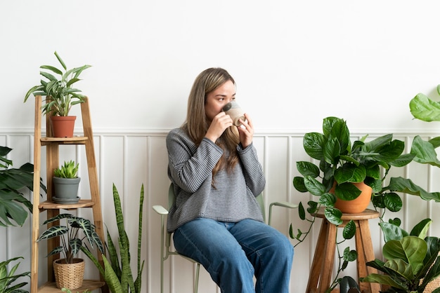 Plant lady resting and sipping team in her plant corner