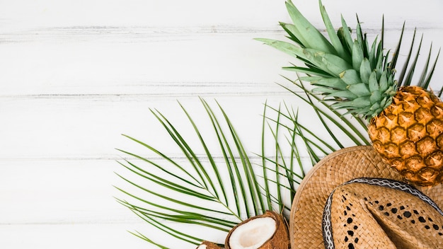 Plant leaves near tropical fruits and hat