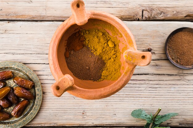 Plant twig near dried fruits and spices in bowl