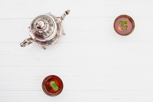 Plants in cups of tea near vintage kettle