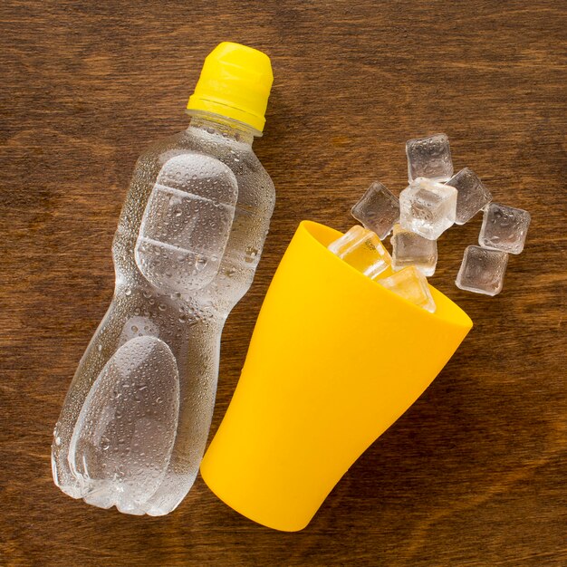 Пластиковая бутылка воды и льда в чашке