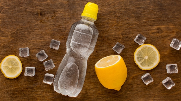 Free photo plastic bottle of water and lemon top view