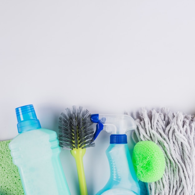 Plastic bottles brush, mop head and sponge on grey background