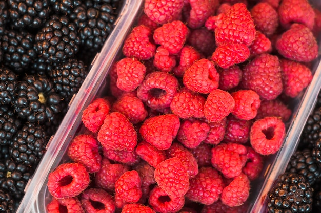 Plastic crate with red raspberries and blackberries