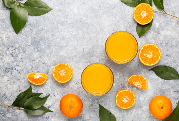 Plastic mini bottles of organic fresh orange juice with raw oranges and tangerines