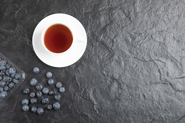 Plastic package of delicious fresh blueberries with cup of hot tea