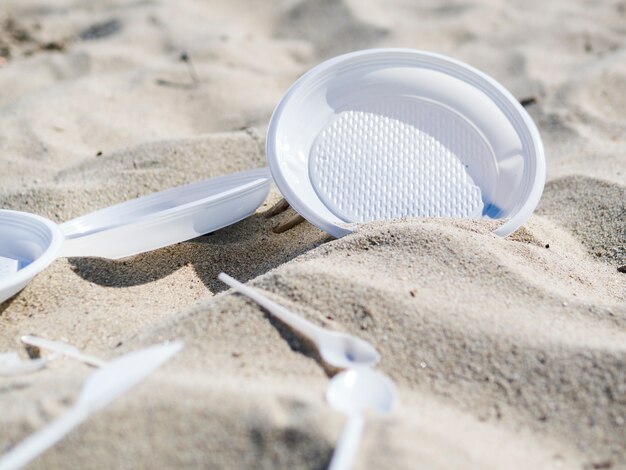 Пластиковая тарелка и ложка на песчаном пляже