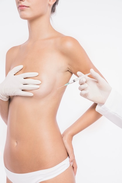Plastic surgeon injecting in woman breast