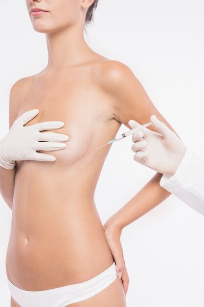 女性の乳房に注入する外科医