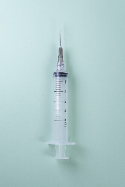 Plastic syringe on green. Top view