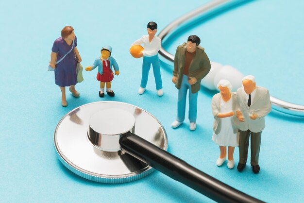 Пластиковые игрушечные фигурки людей и медицинский статоскоп на синем фоне, концепция семейного врача